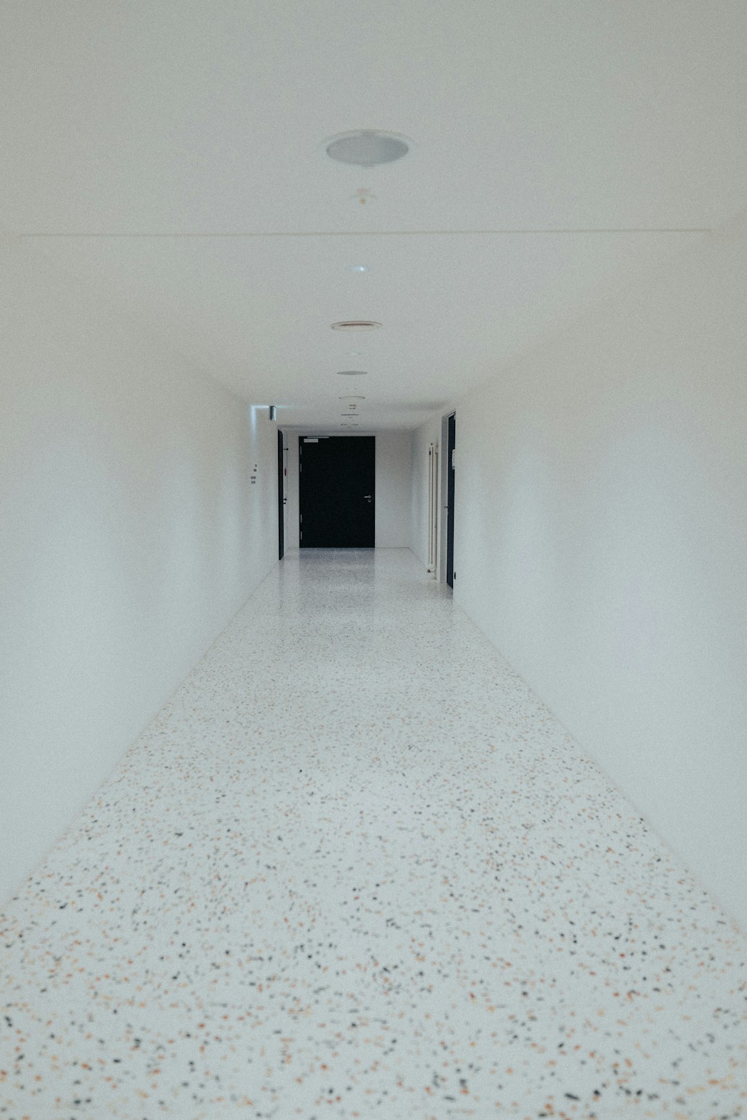 portfolio-02 a-long-hallway-with-white-walls-and-a-black-door-omko6uljkvs